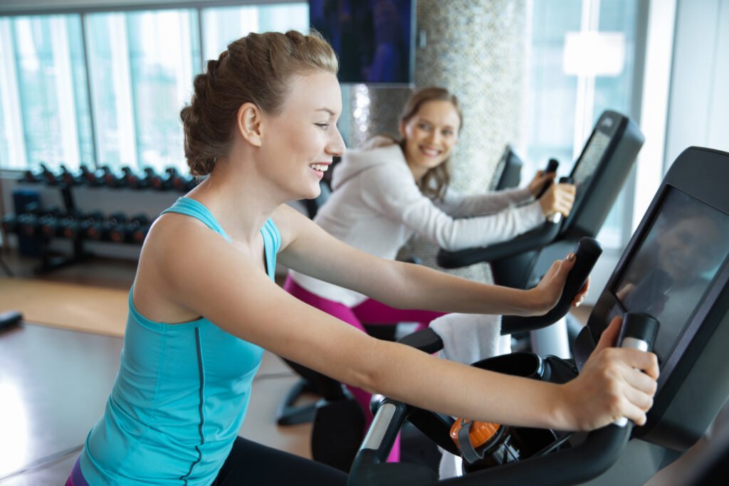 The Silent Power of Consistency happy young woman training on exercise bike in gym